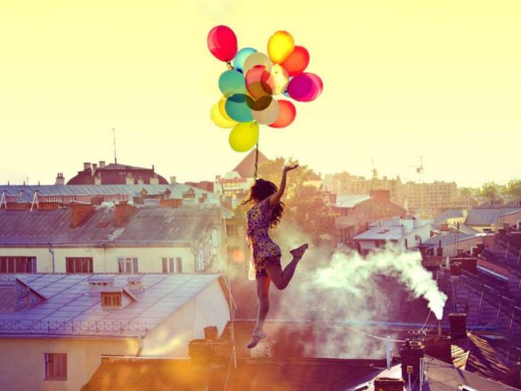 Woman taking a leap of faith holding brightly coloured balloons