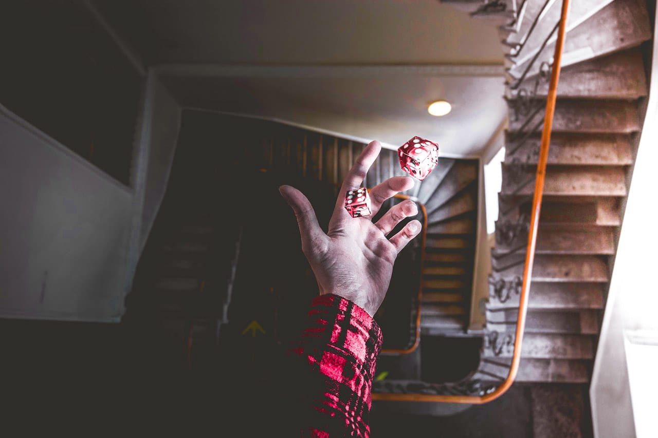 Hand throwing dice over a stairwell